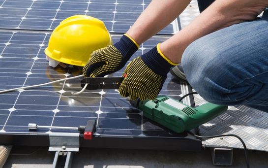 Työntekijä asentaa aurinkopaneelia